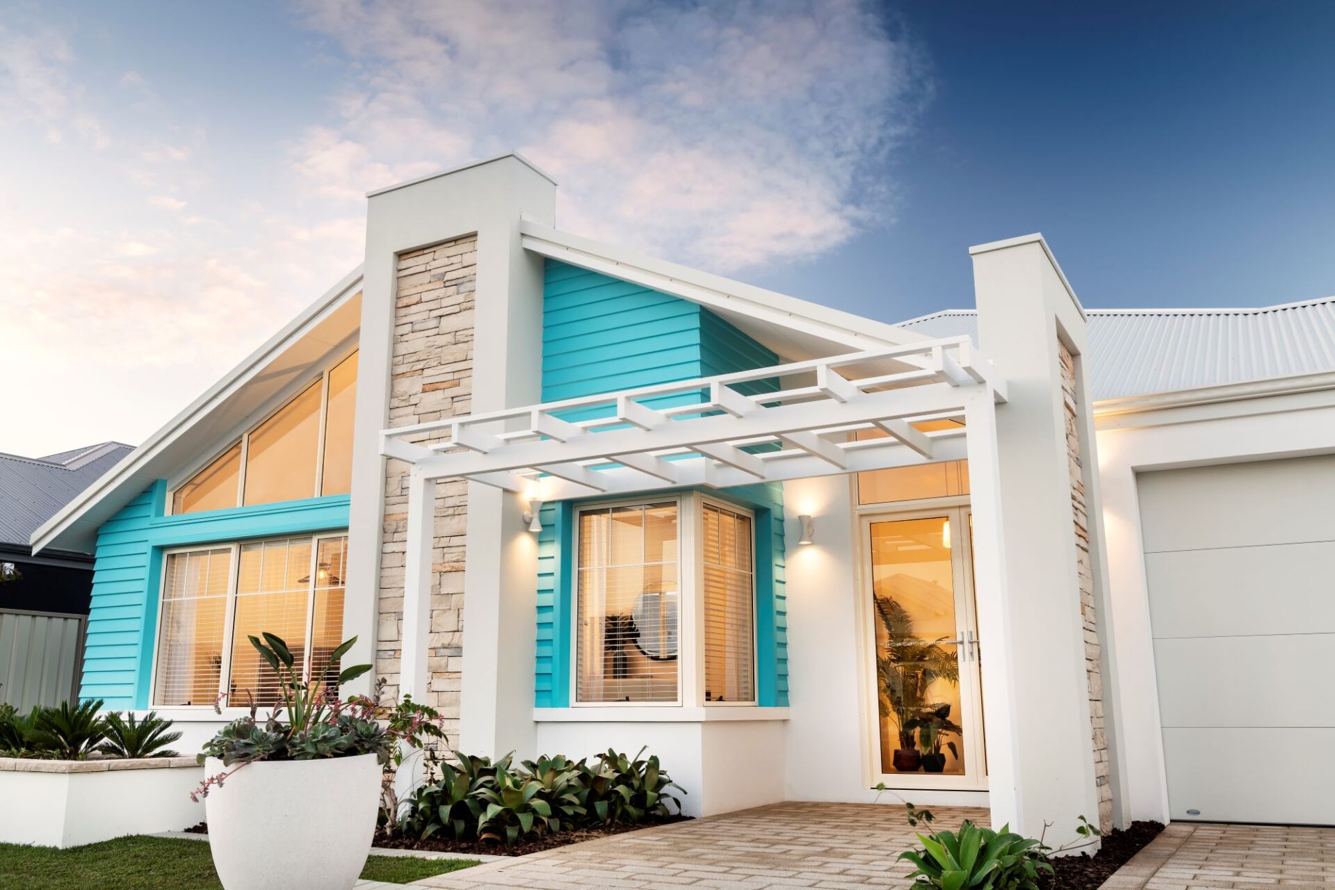 Aqua blue accents on its weatherboard panel detailing on the front facade of the Airlie Beach home design, a striking modern beach house by WA Country Builders.