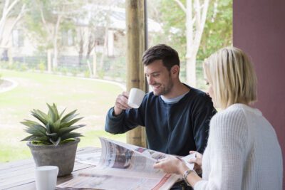 couple sitting together in alfresco reading paper and drink coffee