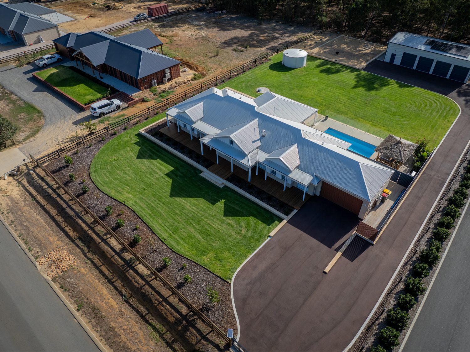 Situated in the picturesque Darling Downs, this aerial view shows a beautifully designed farmhouse with a four door garage situated at the back of the home with a long-extended driveway down the side of the home. Built by WA Country Builders.