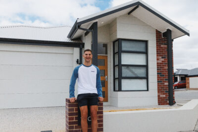 Andrej beaming proudly at the front of his new home, built by WA Country Builders.