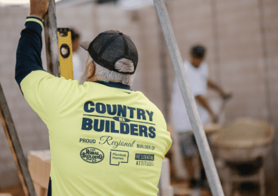 Tradesperson using a level while wearing a Country Builders shirt